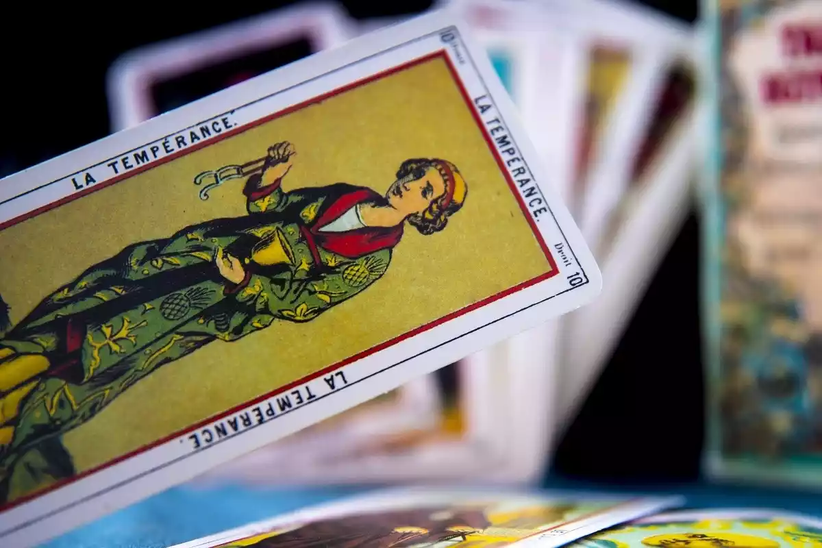 Una carta de tarot con otras muchas detrás en una mesa