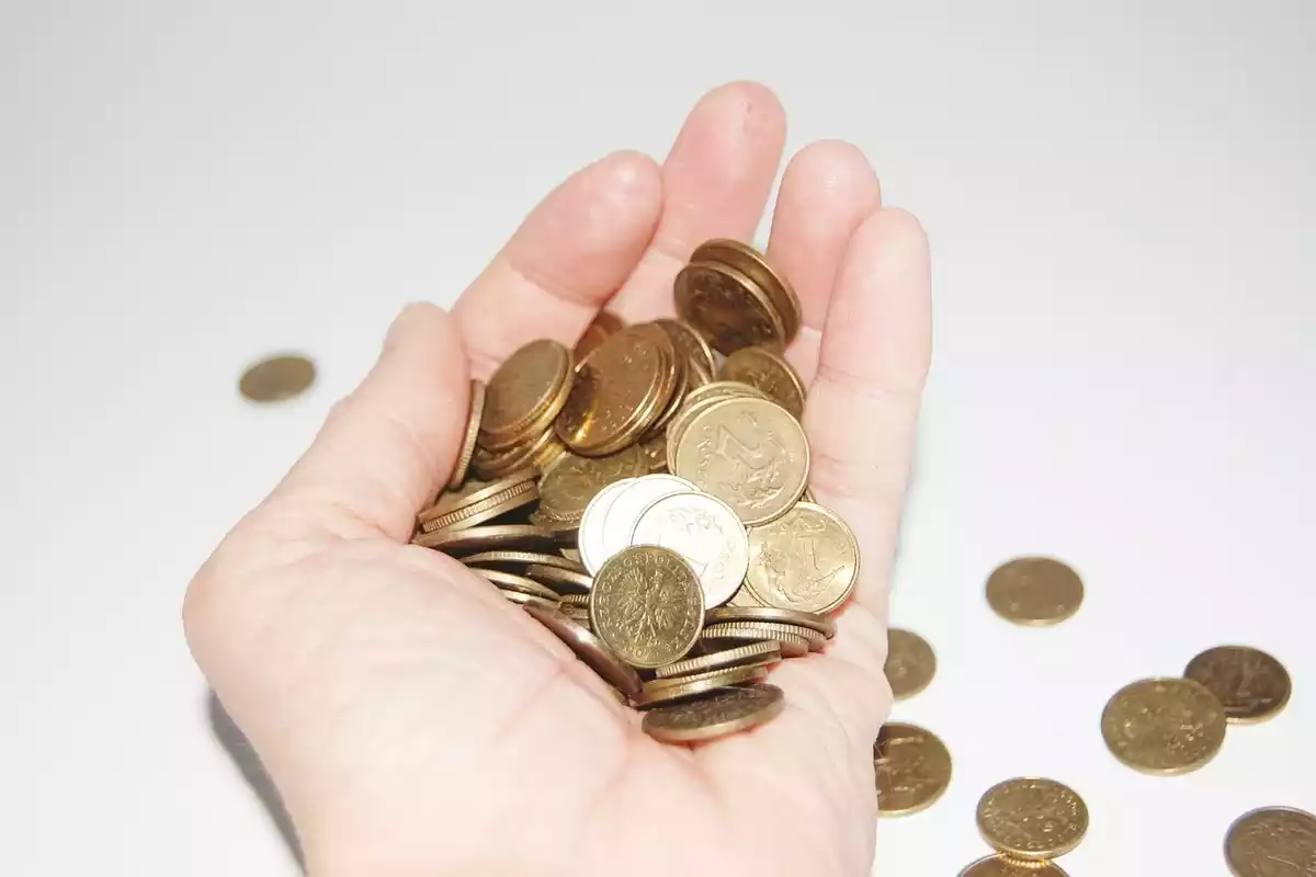 Fotografía de una mano con un puñado de monedas