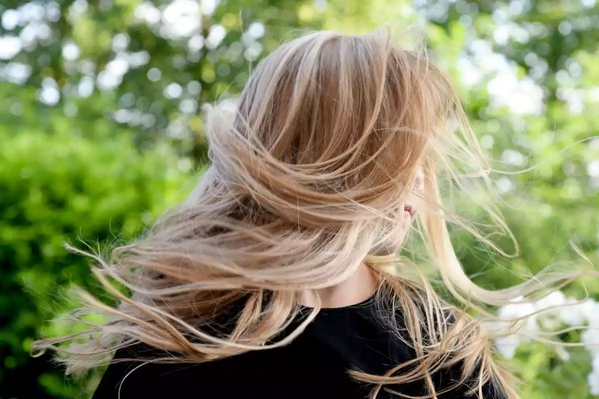 Una mujer con una larga melena de pelo rubia y camiseta negra, en la calle