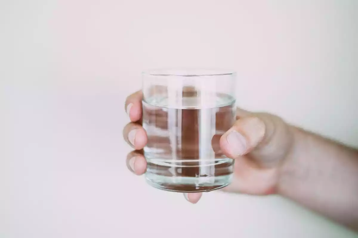 Foto de una mano sosteniendo un vaso de agua