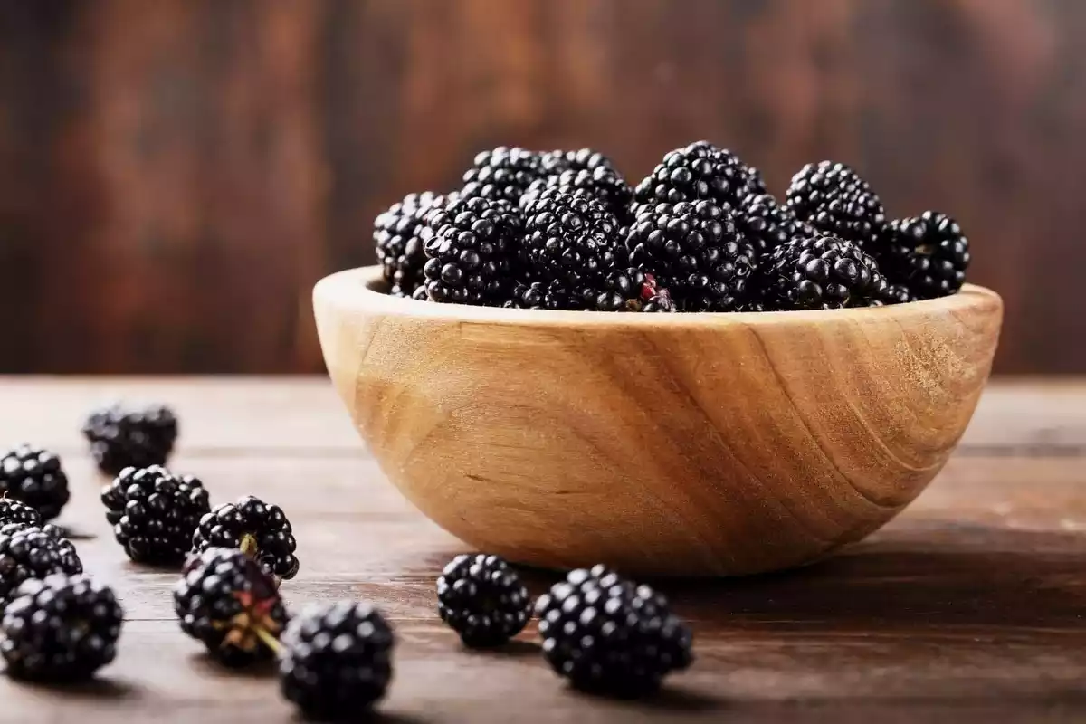 Moras negras en un bol grande de madera encima de la mesa