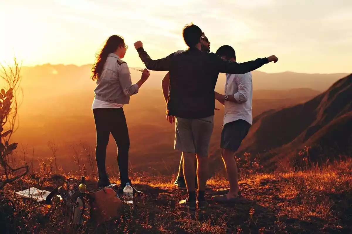 Grupo de 4 personas en un paisaje de montaña al atardecer