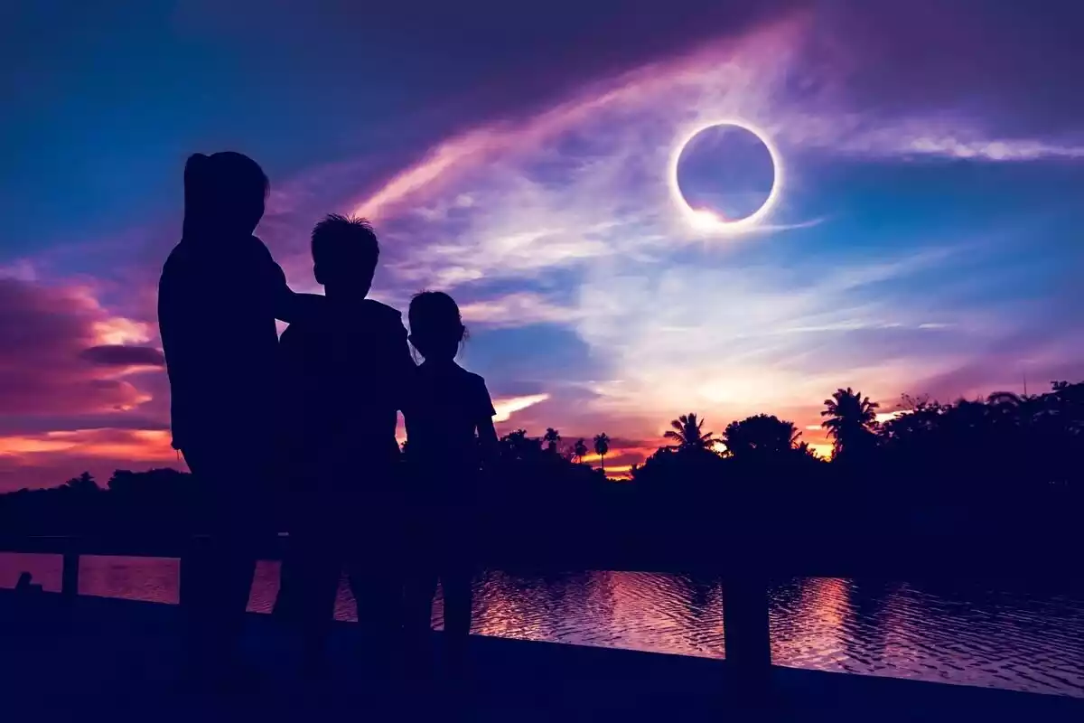 3 personas mirando un eclipse parcial de sol