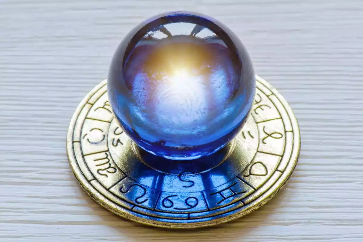 Una bola de cristal para la adivinación de color azul sobre una placa de metal dorada con los Signos del zodiaco inscritos