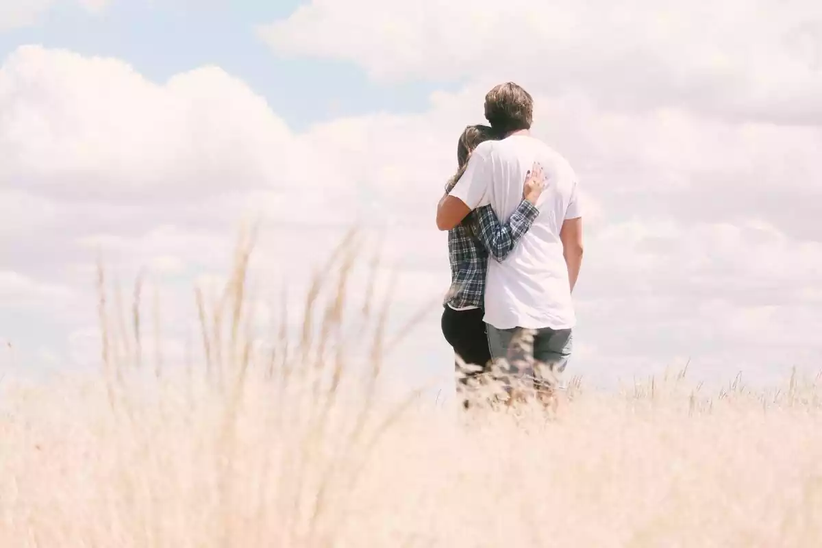 Imagen de una pareja abrazándose con el cielo nublado de fondo