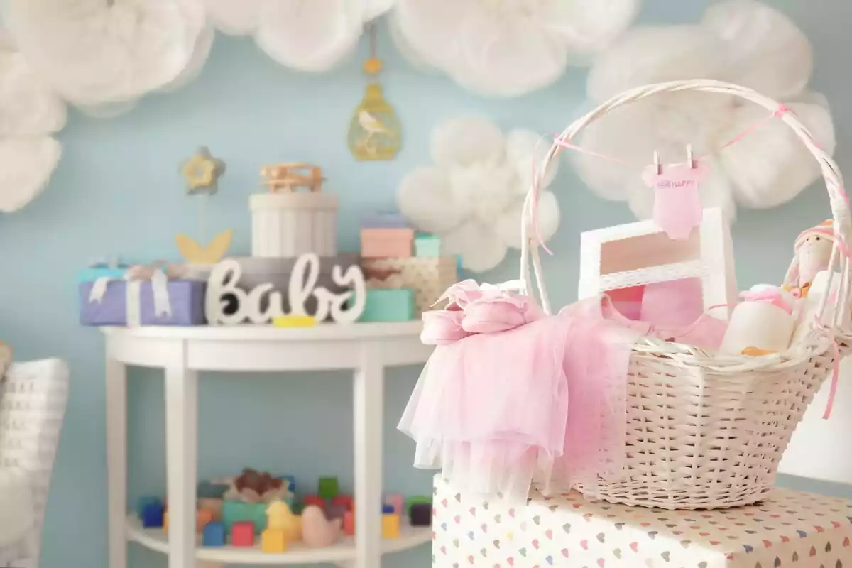 Fiesta de bienvenida al bebé con una cesta encima de un regalo y flores pegadas en la pared