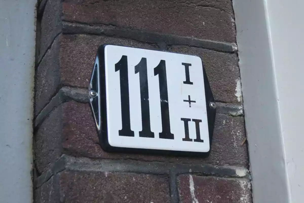 Número 111 en una placa blanca y negra atornillada a la pared