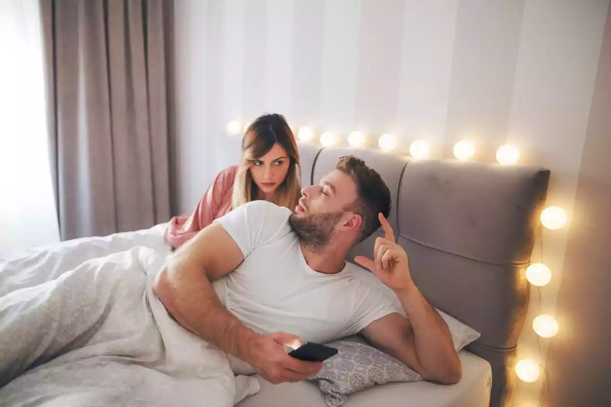 Pareja en la cama con la chica mirando el móvil del chico