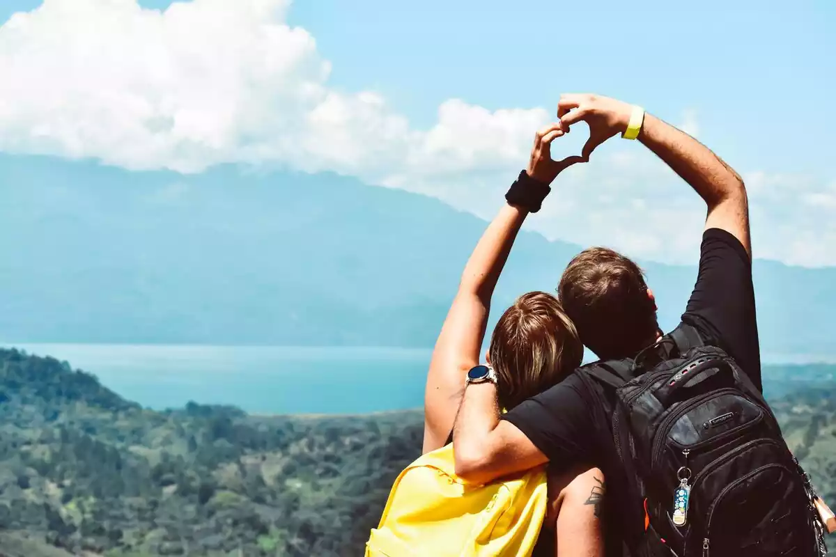 Pareja que forman un corazón con sus anos y de fondo unas montañas