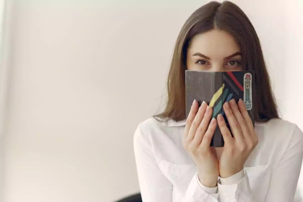 Una mujer tapándose la cara con una libreta