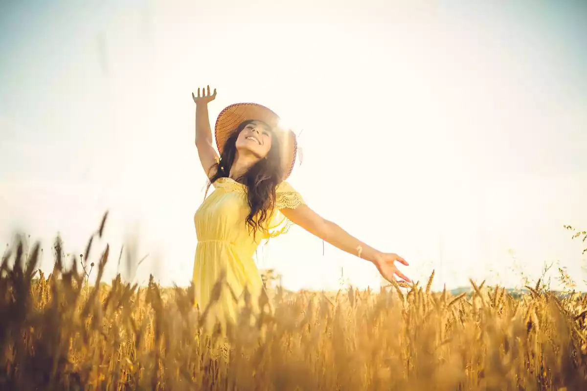 Imagen panorámica de una chica en medio de un campo de espigas sonriendo