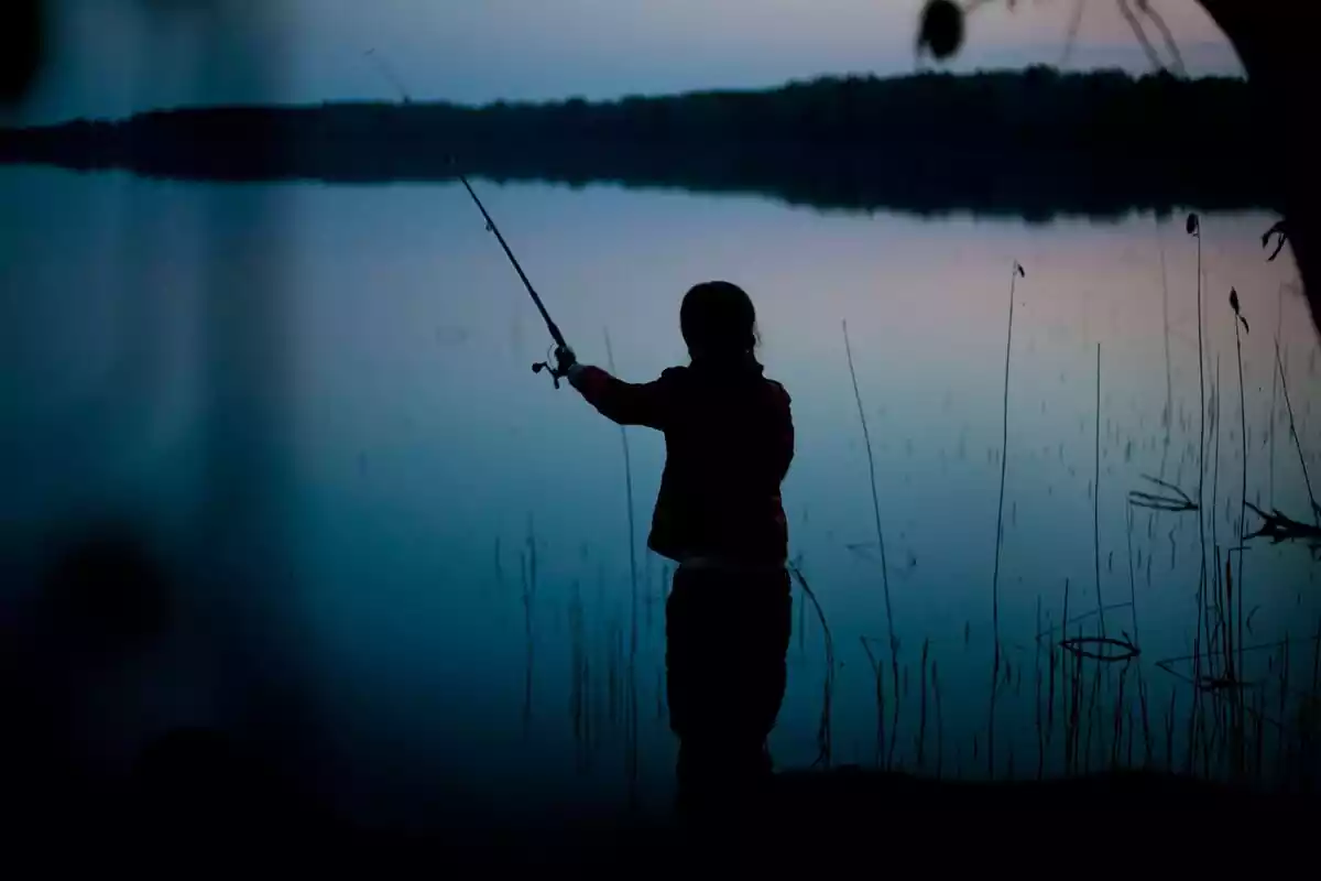 La silueta de una persona de espaldas pescando