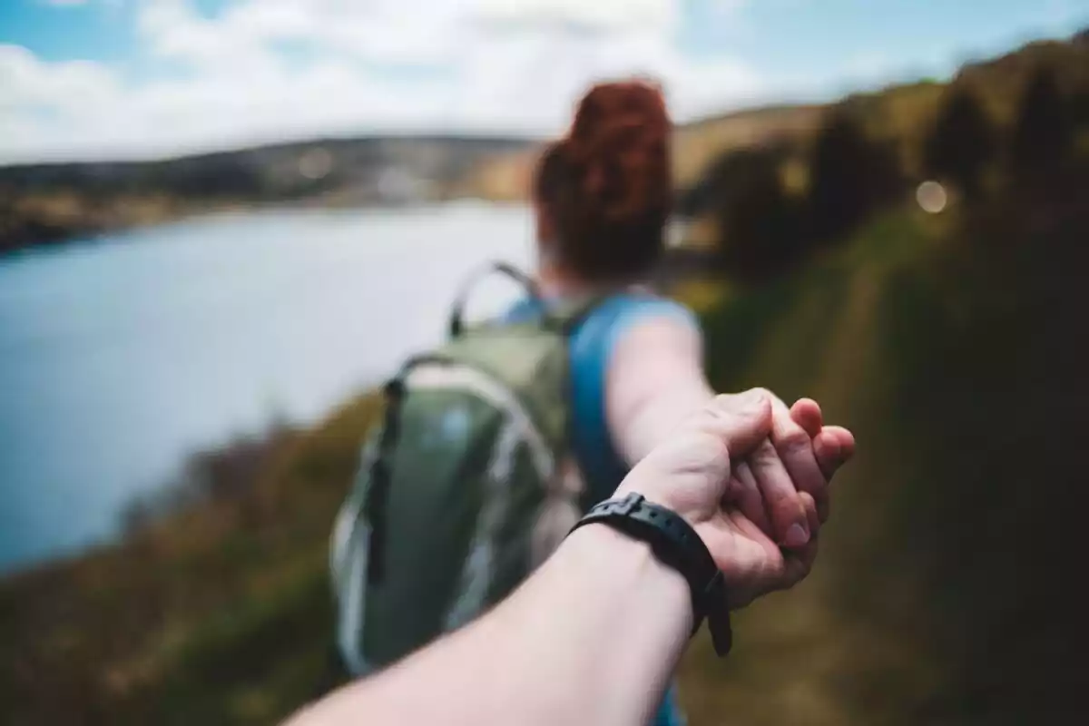 Mujer cogiendo la mano de su pareja en un paisaje