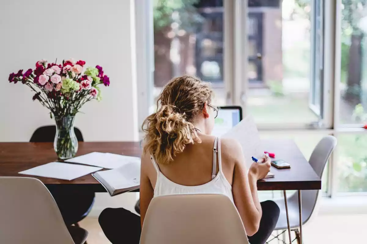 Una chica estudiando sentada en una silla en una mesa