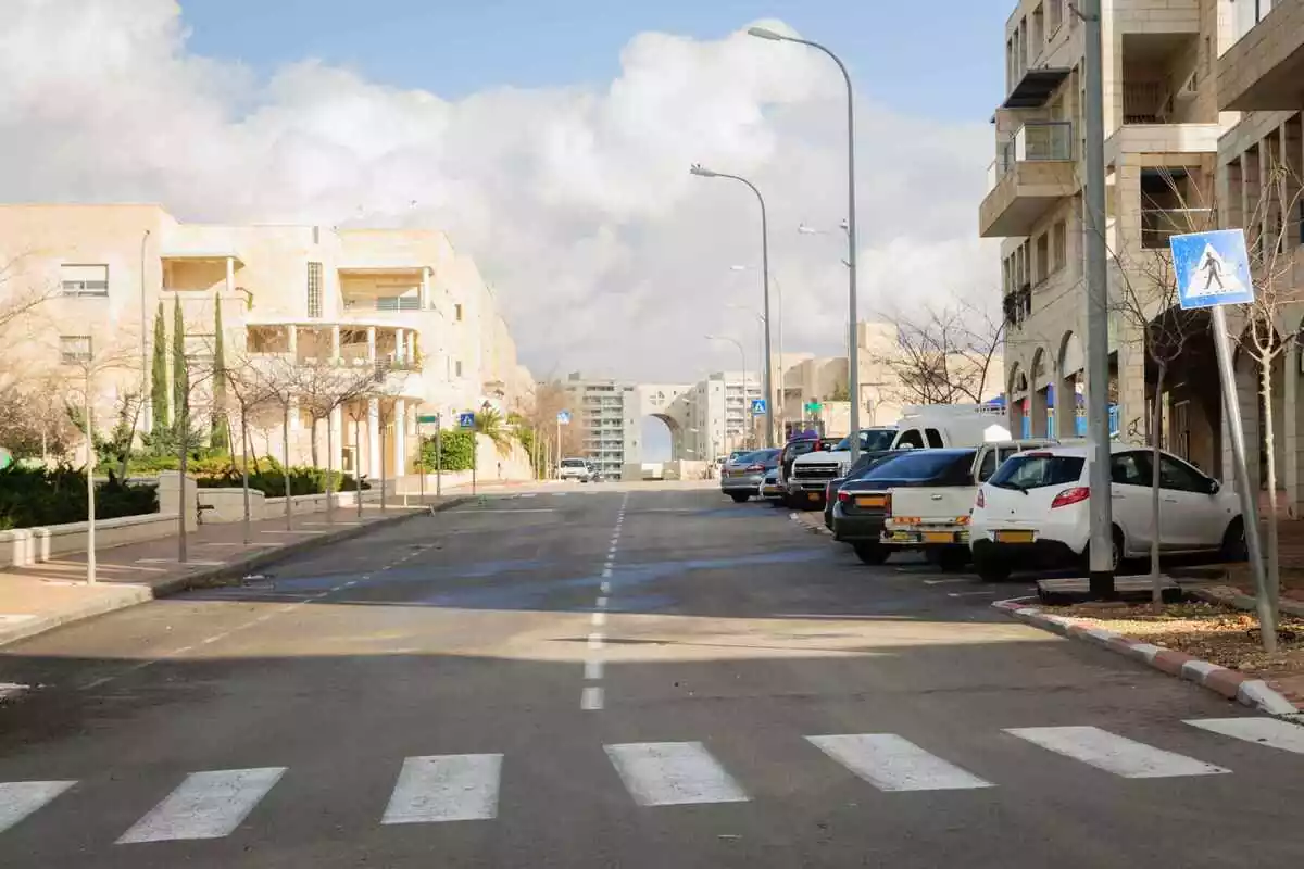 Plano general de la carretera de una ciudad con un paso de peatones y coches aparacados a la derecha