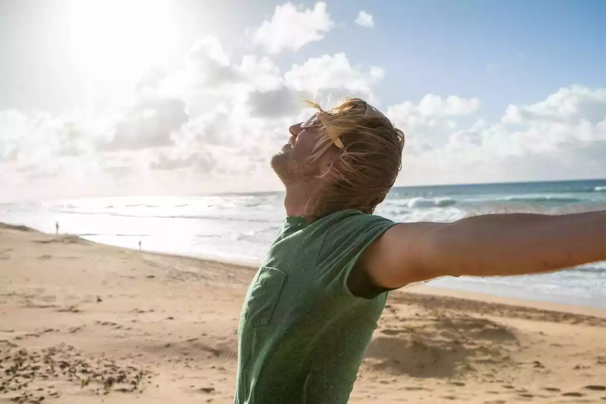 Un chico con los brazos extendidos mirando hacia el sol