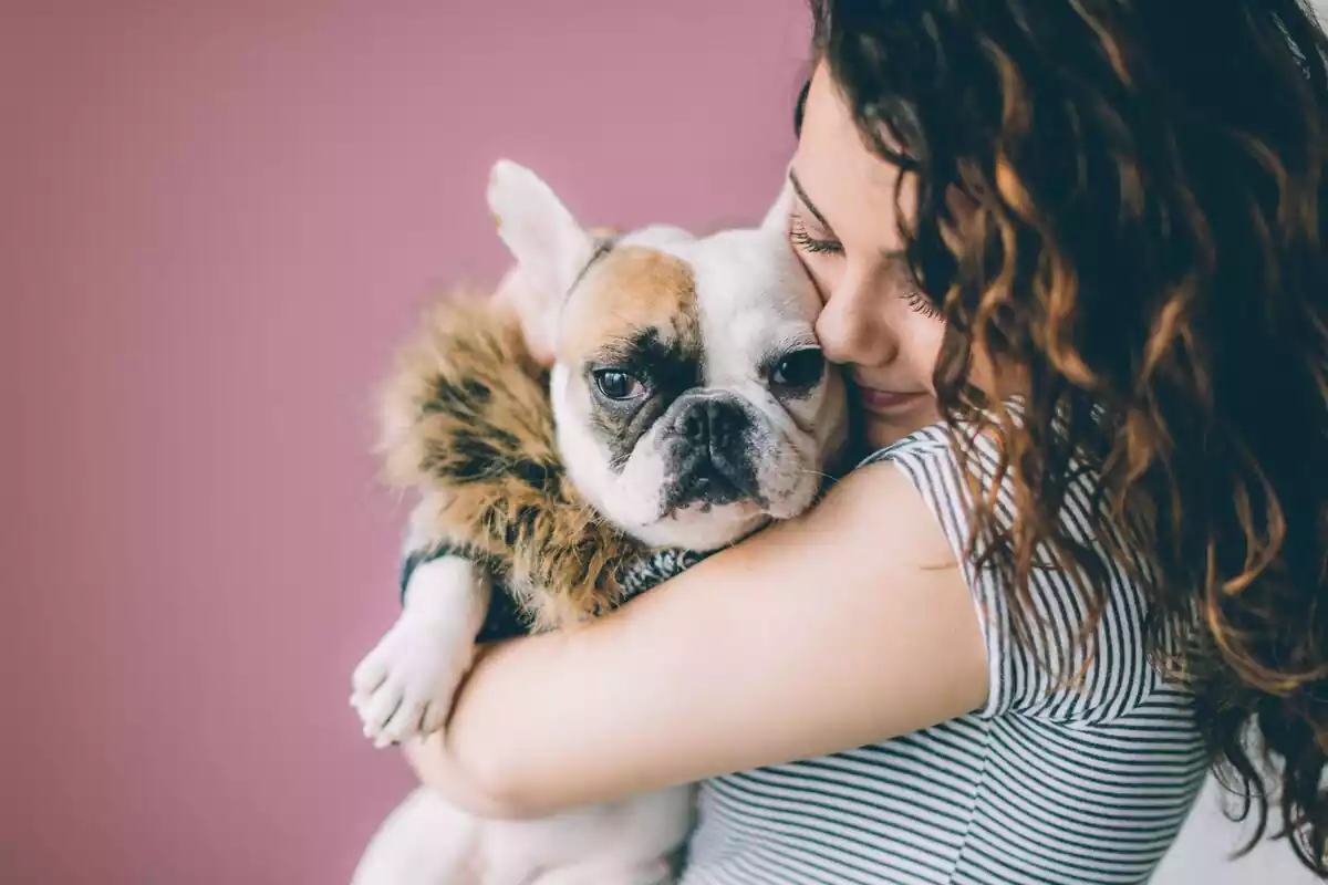 Una chica con un perro en brazos