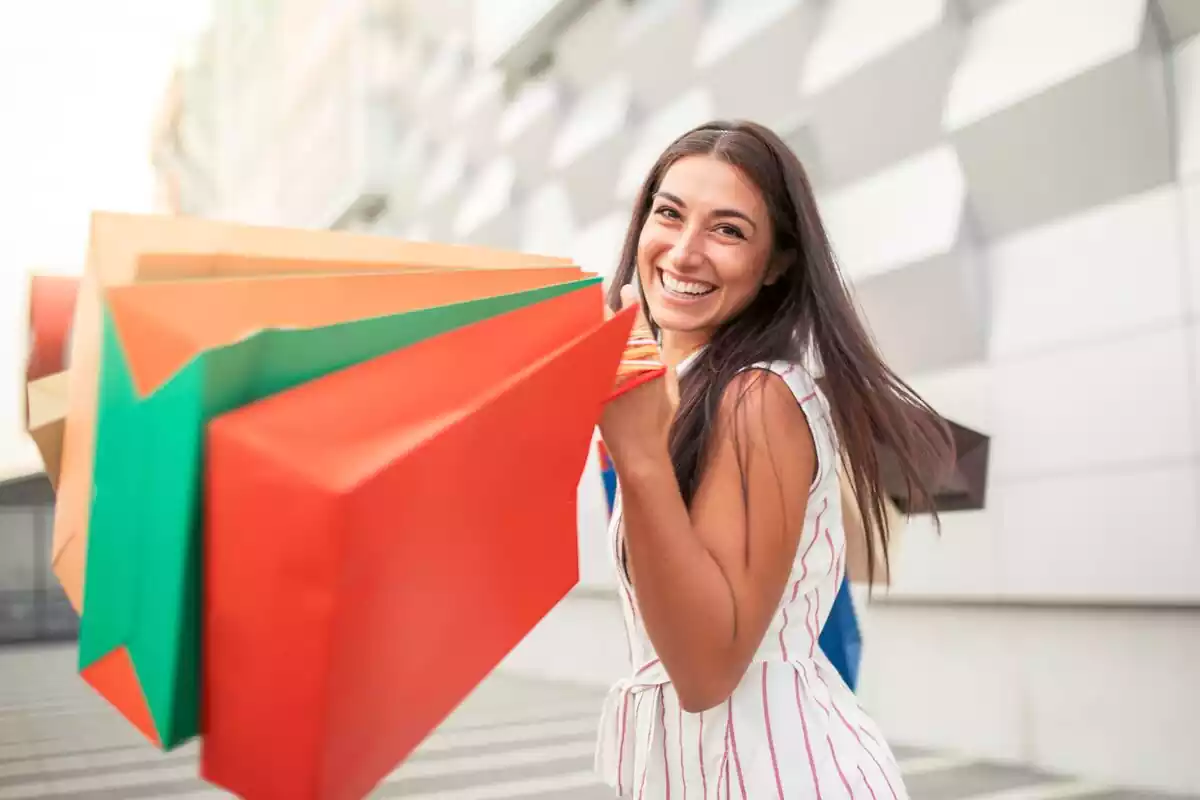 Una chica con una sonrisa y unas bolsas de compras en las manos