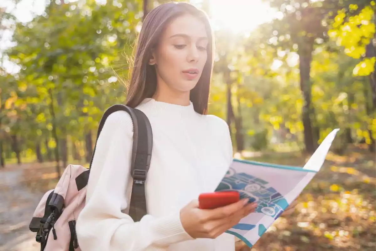 Una chica concentrada mirando un mapa y su teléfono móvil