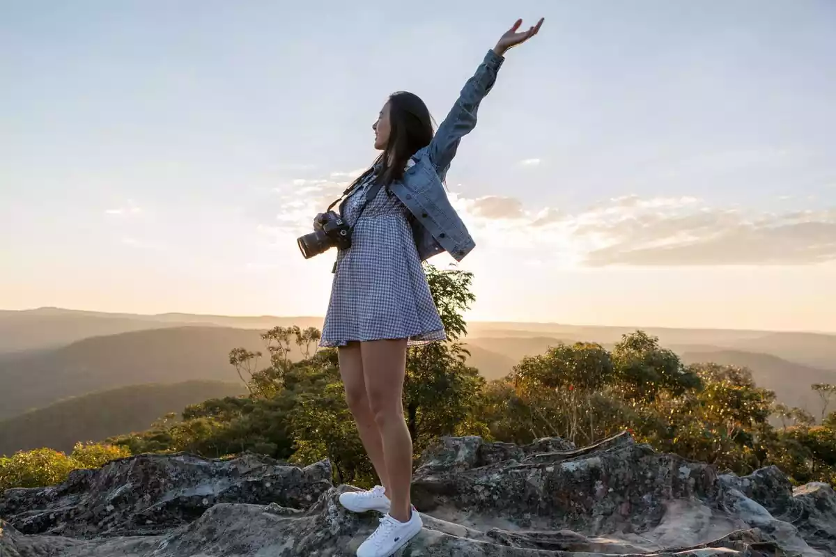 Una chica feliz con una cámara de fotos y levantando los brazos