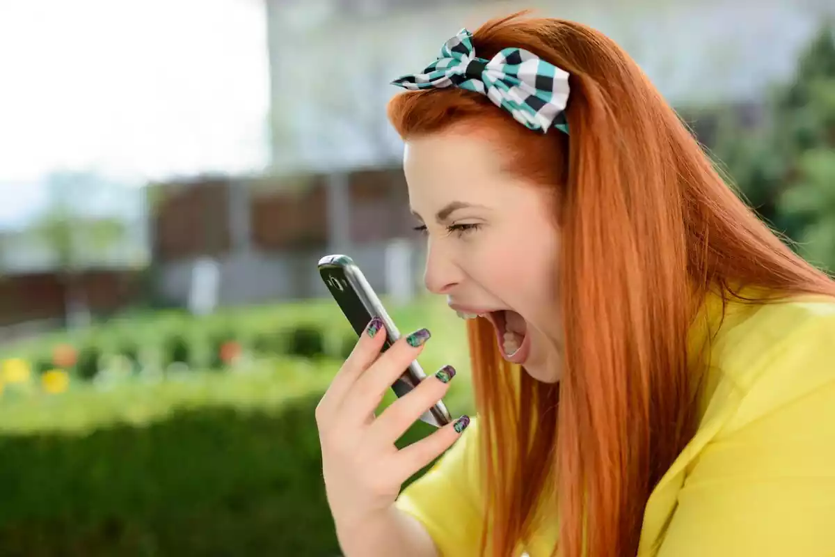 Una mujer pelirroja gritando al teléfono móvil