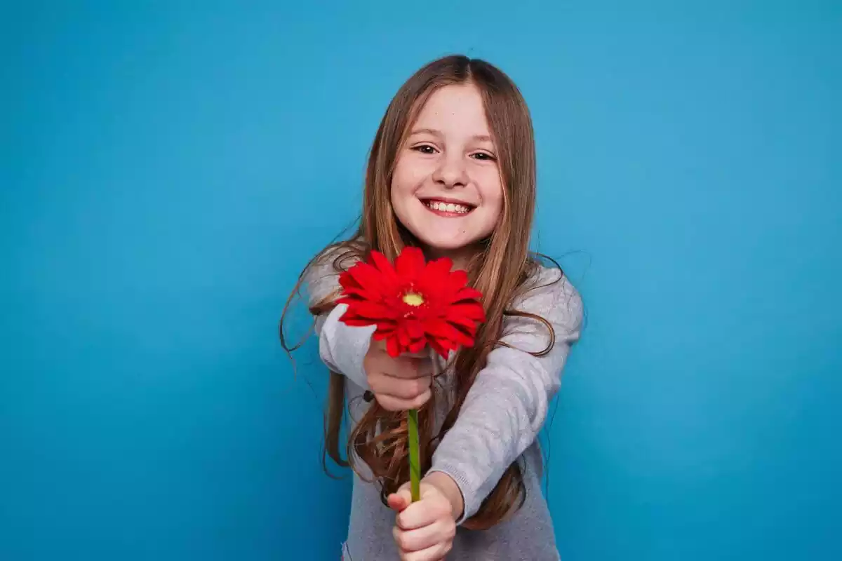 Una niña con una flor en las manos y un fondo de color azul