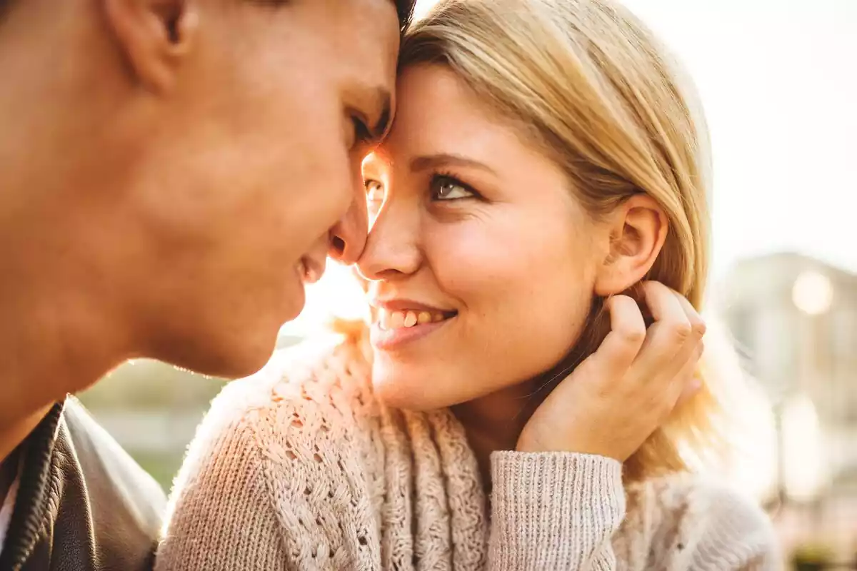 Una pareja joven mirándose a los ojos y apoyando sus frentes