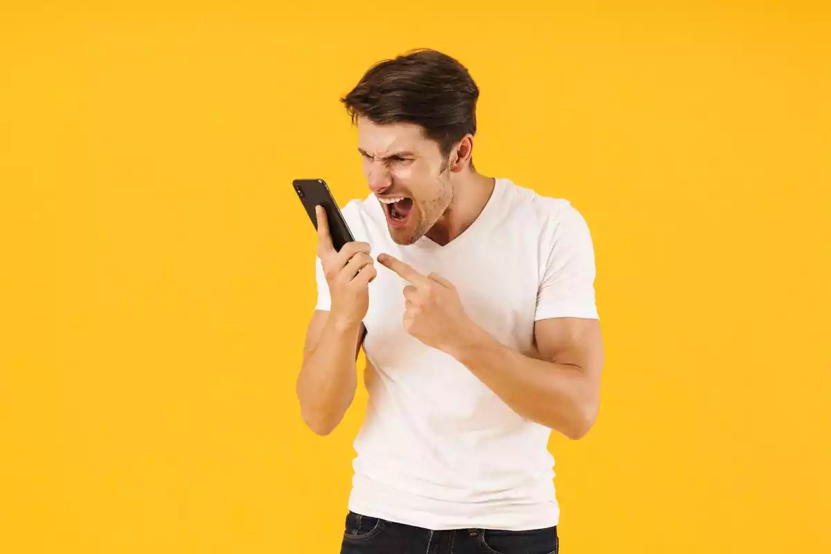 Hombre gritando a su teléfono móvil en un fondo amarillo