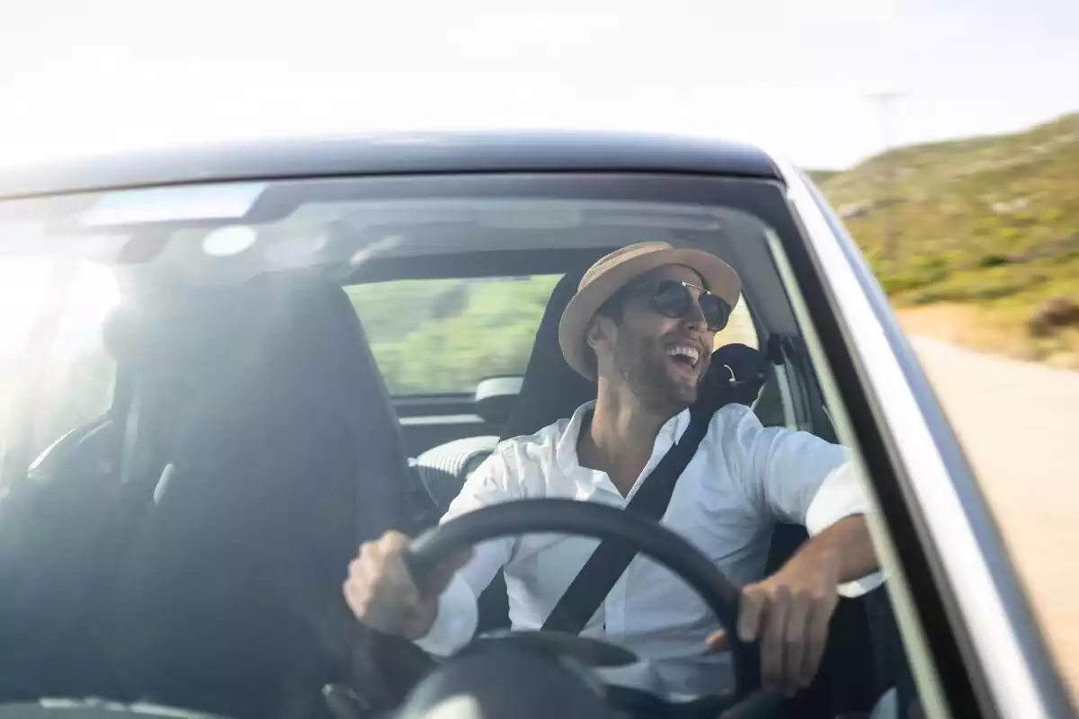 Un chico conduciendo un coche sonriendo