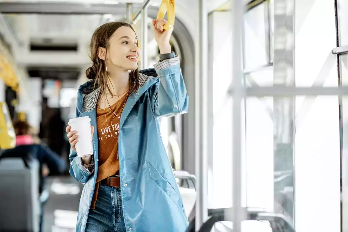 Una chica en un tranvía con un café en la mano