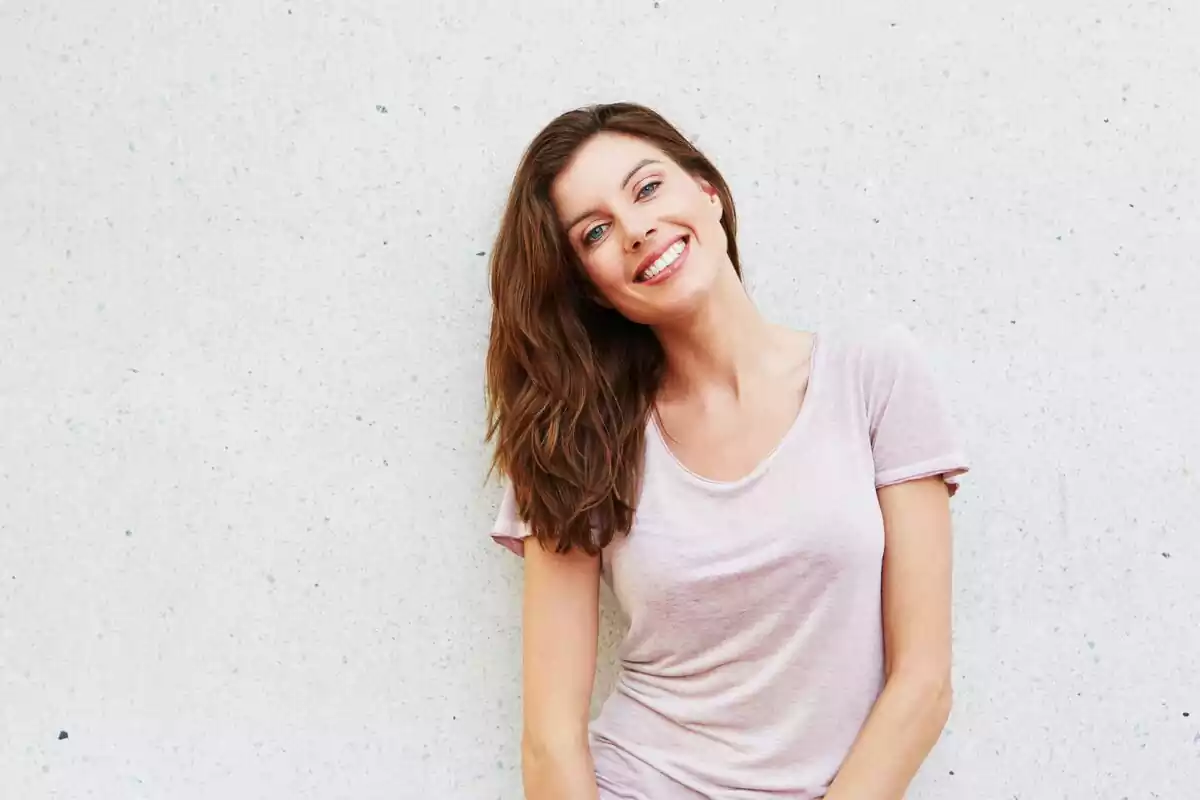 Una mujer sonriendo sobre un fondo blanco