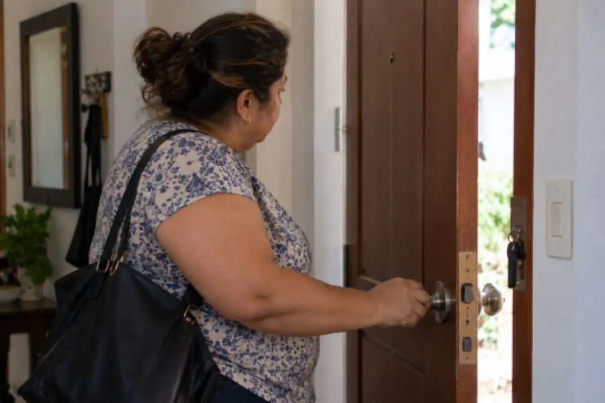 Mujer con bolso abriendo la puerta principal de una casa desde el interior. Mujer con bolso abriendo la puerta principal de una casa desde el interior.